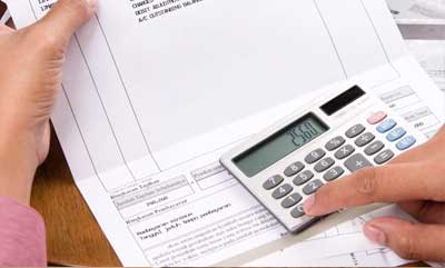 A first person view of holding financial papers at a desk and pressing buttons on a calculator