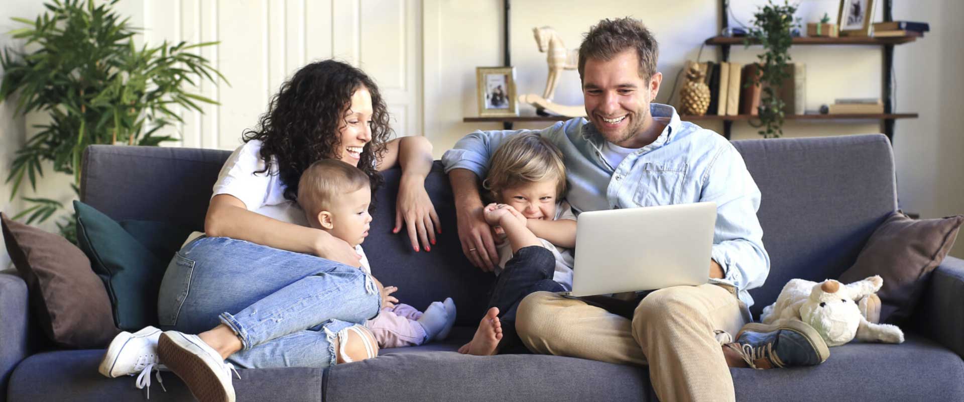family sitting down on a sofa looking at the family laptop