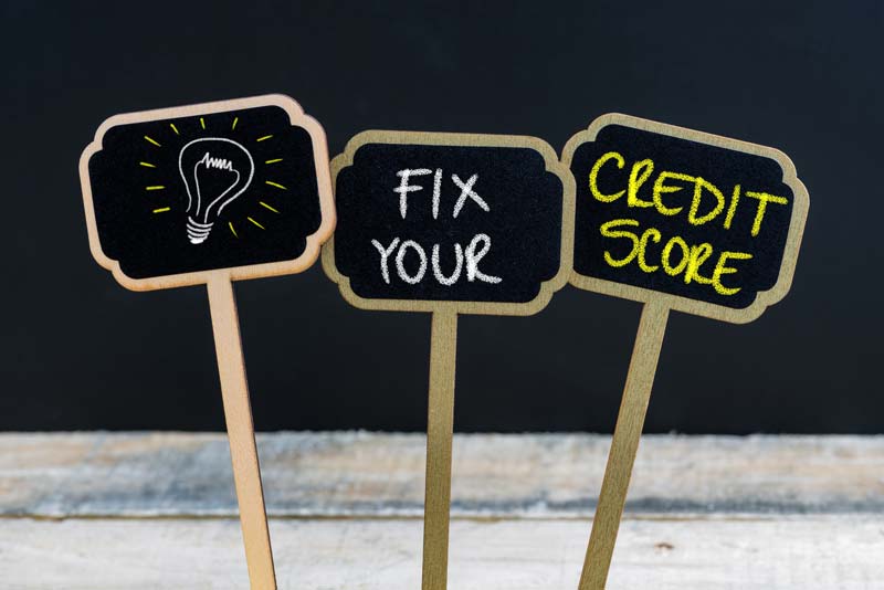 From left to write, a sign has a light bulb drawing on it, the middle sign has Fix Your written on it, and the sign on the right reads Credit Score