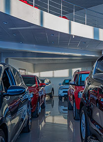 A picture looking between two rows of cars in a dealership showroom.