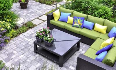 A nice patio sitting area with a large outdoor sectional, surrounded by lush garden plants